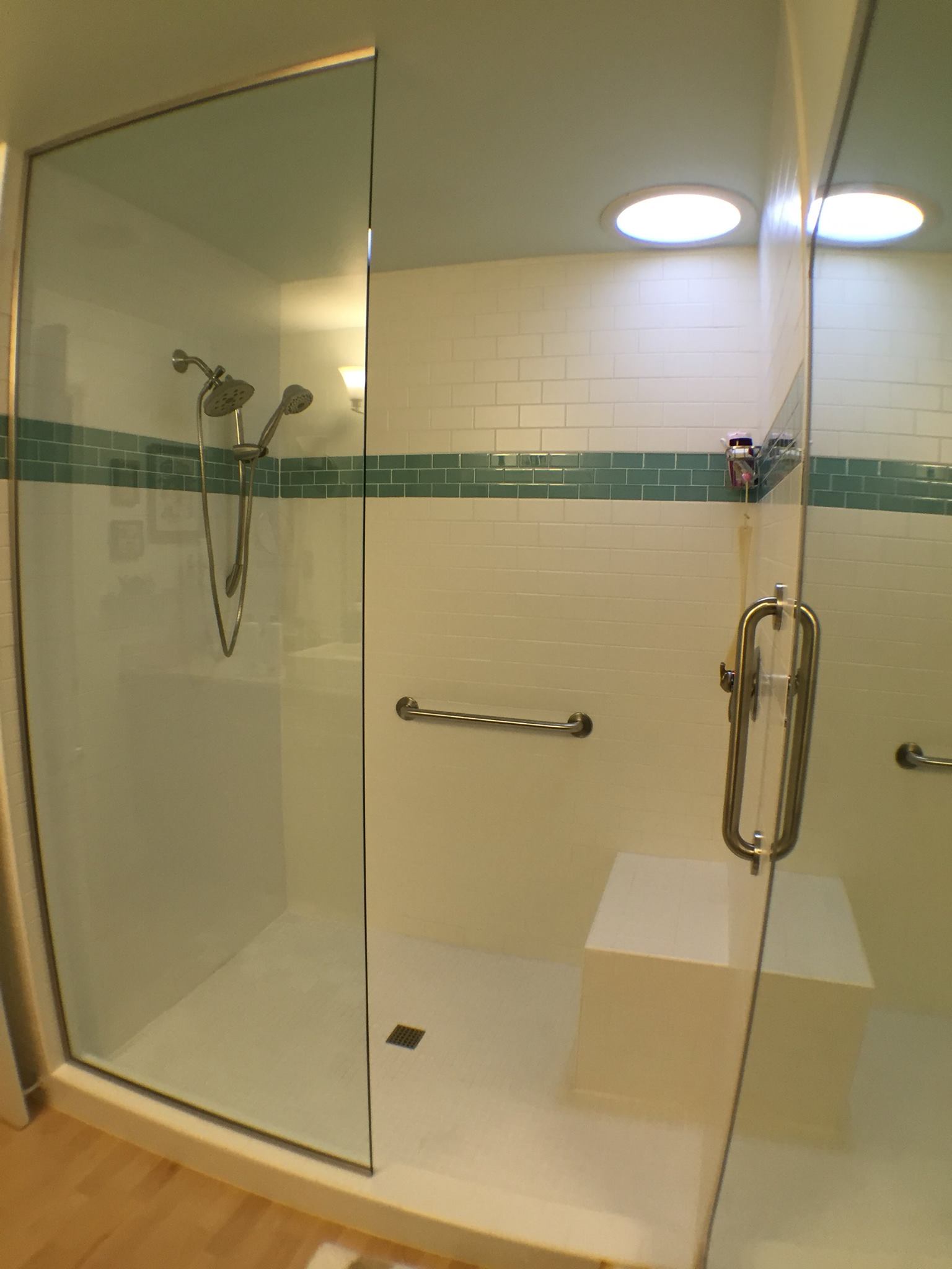 Shower with while tile walls and a strip of dark teal running through