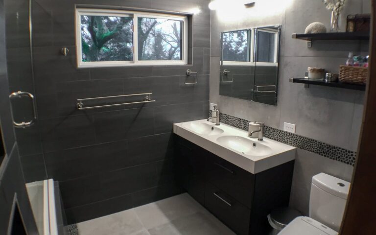 Remodeled bathroom with black tile and double sink floating vanity