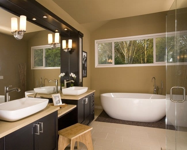 Bathroom with two vessel sinks, a freestanding tub, dark walnut vanity, and tan walls