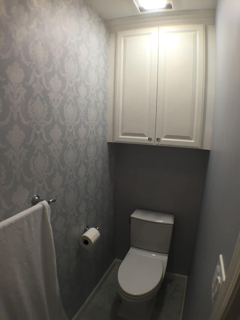 Toilet room with patterned walls and a simple white cabinet
