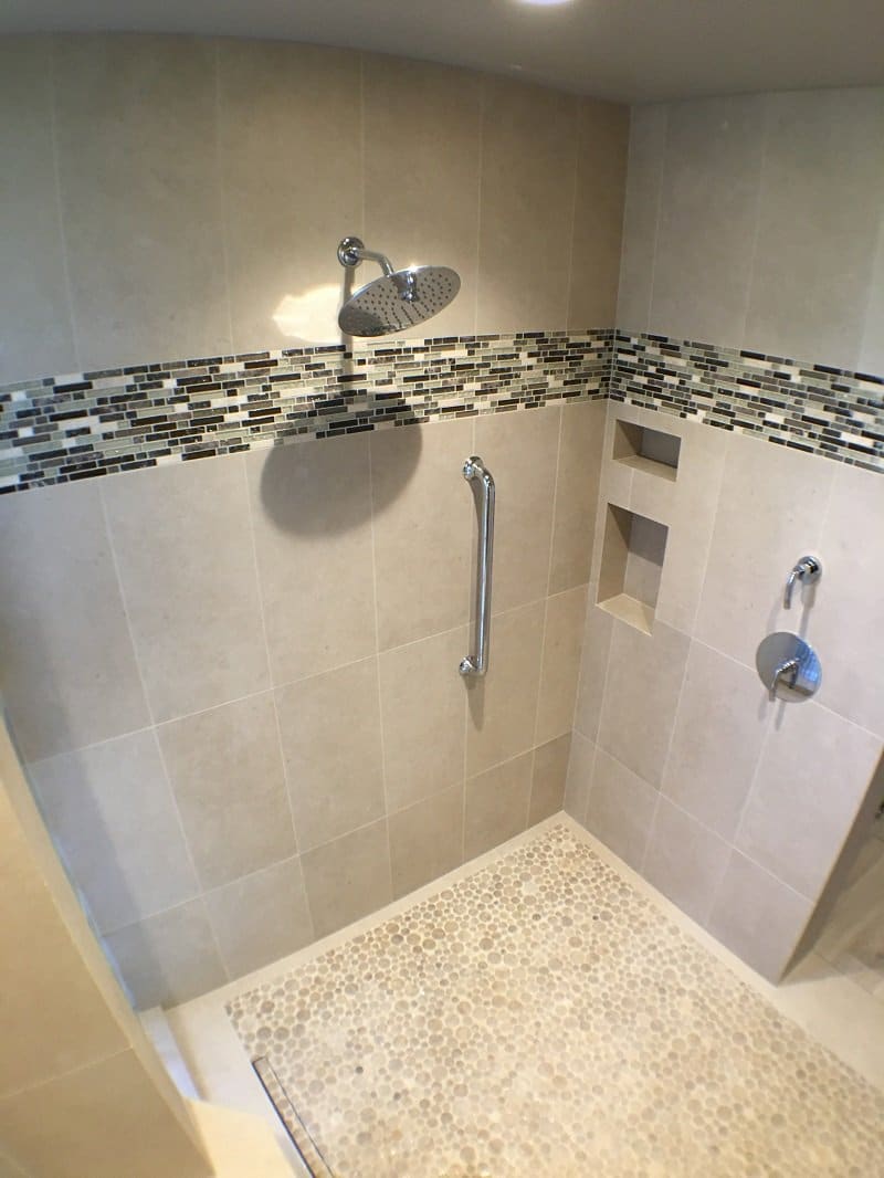 Shower with light grey tiling and a multi-colored accent strip of tiles