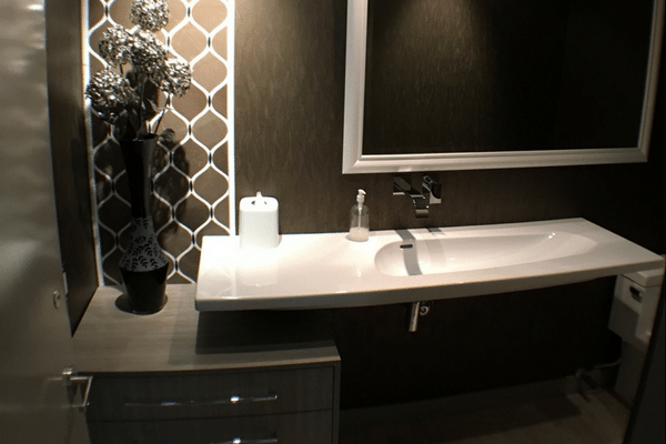 Trough style sink set against a dark brown wall 