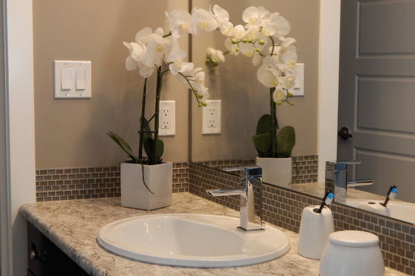 Vanity sink with a white flower set beside it