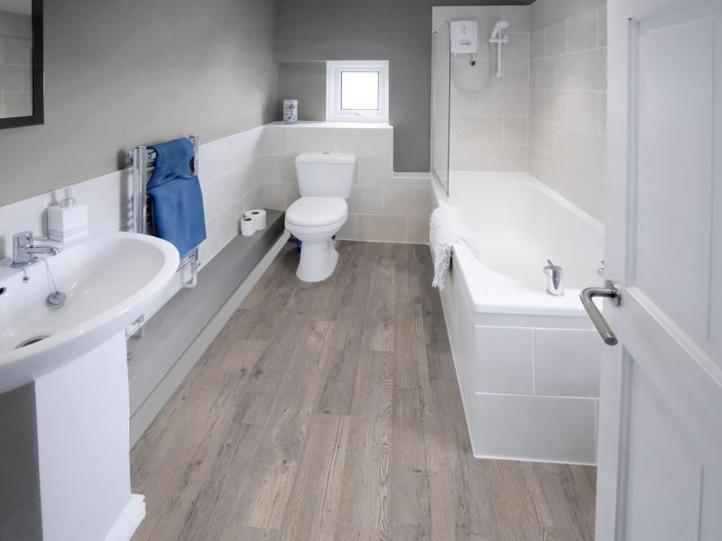 Bathroom with wood flooring and a white toilet, sink, and tub