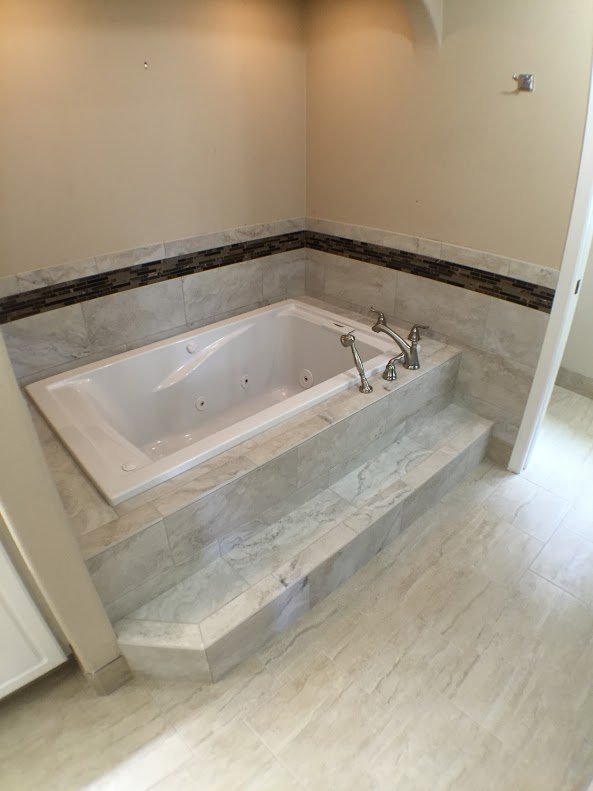 Drop-in tub surrounded by marble tile
